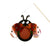A ladybug-shaped hanging wall decoration made from shiny copper-colored metal sheets, black metal parts, and small green accents, suspended by a string from a thin wooden stick against a plain white background.