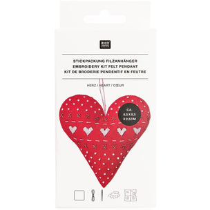 Packaged felt embroidery kit in the shape of a heart, shown in its white retail packaging with German text and a photo of the red embroidered heart.
