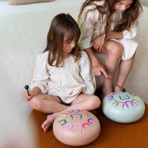Two children playing with colorful instruments on a couch.