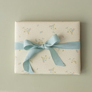 Gift box with floral pattern and blue ribbon on a beige background