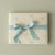 Gift box with floral pattern and blue ribbon on a beige background