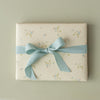 Gift box with floral pattern and blue ribbon on a beige background