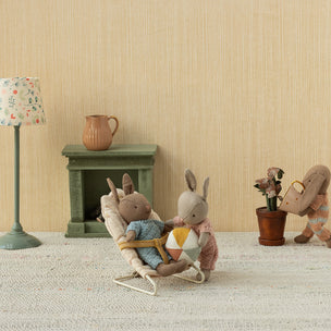 Miniature scene with Maileg bunnies in a room setting, including a lamp, fireplace, and decorative items.