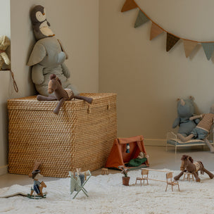 Children's playroom with toys and furniture on a carpeted floor.
