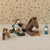 Maileg mouse in cowboy hat and boots sitting on a horse with a lantern and carrot on a patterned background