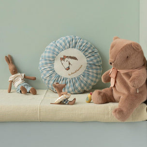 Children's toys including a teddy bear and rabbit on a shelf against a light green wall.