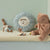 Children's toys including a teddy bear and rabbit on a shelf against a light green wall.