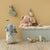 Children's room with plush toys and a toy chest against a beige wall.