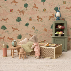 Miniature Maileg room setup with a doll, furniture, and decorative elements against a wallpaper with horse pattern.