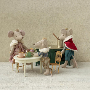 Miniature Maileg mouse figures in a tea party scene with a decorative wall background.