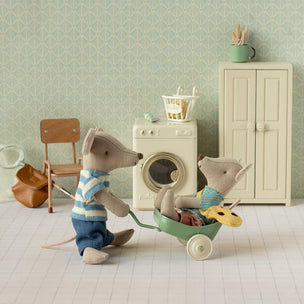 Two toy Maileg mice in a miniature room with a washing machine and furniture.