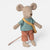 A plush toy Maileg mouse doll with beige fabric body and ears, wearing a blue and yellow striped shirt, peach pants, and a yellow crossbody bag, photographed on a clean light gray background.