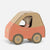 A small Maileg in car, with a brown cardboard body, peach-pink lower section, and gray wheels, photographed on a clean light gray background.