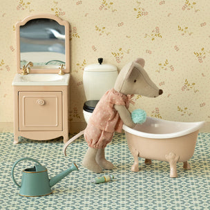 Toy mouse in a bathtub with bathroom furniture and decor in the background