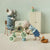 Two toy maileg mice in a room with a tricycle and other items.