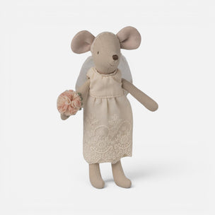 A small Maileg mouse doll with beige fabric body, large pinkish-brown ears, a white veil, and a cream dress with lace trim, holding a pink fabric flower bouquet against a light gray studio background.