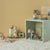 Miniature dollhouse with furniture and accessories on a soft surface against a beige wall.