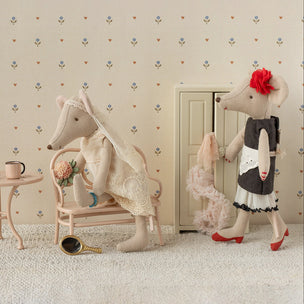Two plush Maileg mice in a decorative room with wallpaper and furniture.
