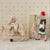 Two plush Maileg mice in a decorative room with wallpaper and furniture.
