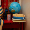 Globe on a red table with books and a canister in a room setting