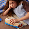 Young girl lying on a bed with a blanket, holding a small plush toy.