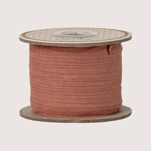 Spool of pink maileg ribbon on a beige background