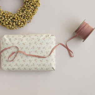 Gift wrapped in floral paper with pink ribbon on a light background