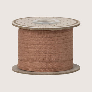 Spool of brown Maileg ribbon on a white background