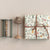 Gift box with floral pattern and brown ribbon on a beige wall with decorative items.