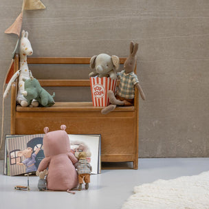 Stuffed animals on a wooden bench with a mirror, popcorn, and photo frame.