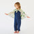 Child wearing a blue outfit with a patterned cape on a white background