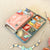Bead kit with colorful beads and tools on a beige surface