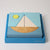 Grimm's Wooden puzzle toy shaped like a sailboat in a blue box on a light gray background