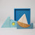 Grimm's Wooden sailboat toy with a blue tray on a light gray background
