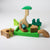 Grimm's Wooden toy set with green base and various wooden pieces on a white background