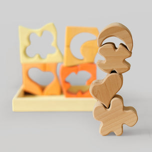 Grimm's Wooden shape sorter with various cut-out shapes on a gray background