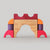 Grimm's Colorful wooden block toy shaped like a castle on a gray background