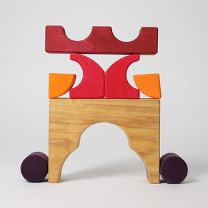Grimm's Wooden toy structure with red, orange, and purple blocks on a white background