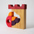 Wooden block toy with red, orange, and purple shapes on a light gray background