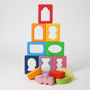 Grmm's Colorful wooden blocks with cut-out shapes stacked on a white background.