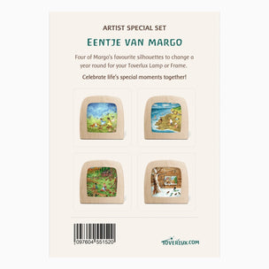 Back of a Toverlux artist special set 'Eentje Van Margo' package, showing four illustrated wooden square frames with colorful landscape scenes, plus product text and a barcode on a cream background.