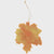 Decorative leaf ornament with a string on a light gray background