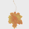 Decorative leaf ornament with a string on a light gray background