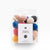 Packaged set of colorful yarn pom-poms with a white label on a light gray background