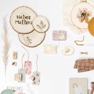 Collection of nature-themed decorative items including wooden slices, tags, and a embroidery hoop with flowers on a white background.