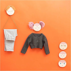 Children's clothing and accessories on a bright orange background with decorative face masks.