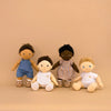 Four dolls with different skin tones and hairstyles on a beige background