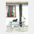 Illustration of a cat and chickens by a window with a red frame.