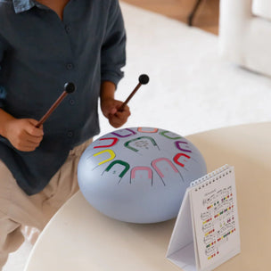 Child playing with a colorful ball and mallets on a couch