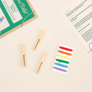 Wooden clothespins and a set of rainbow-colored clothespins on a beige surface with instructions.